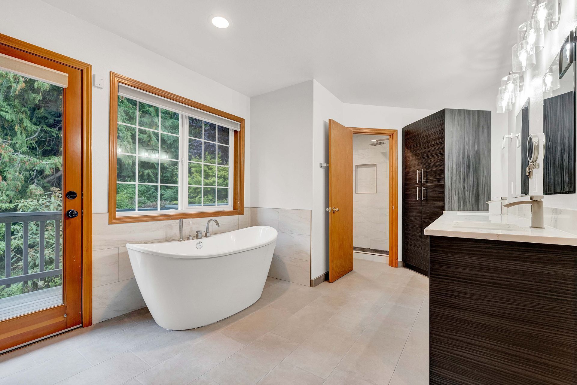 A bathroom with a tub , sink , mirror and window.