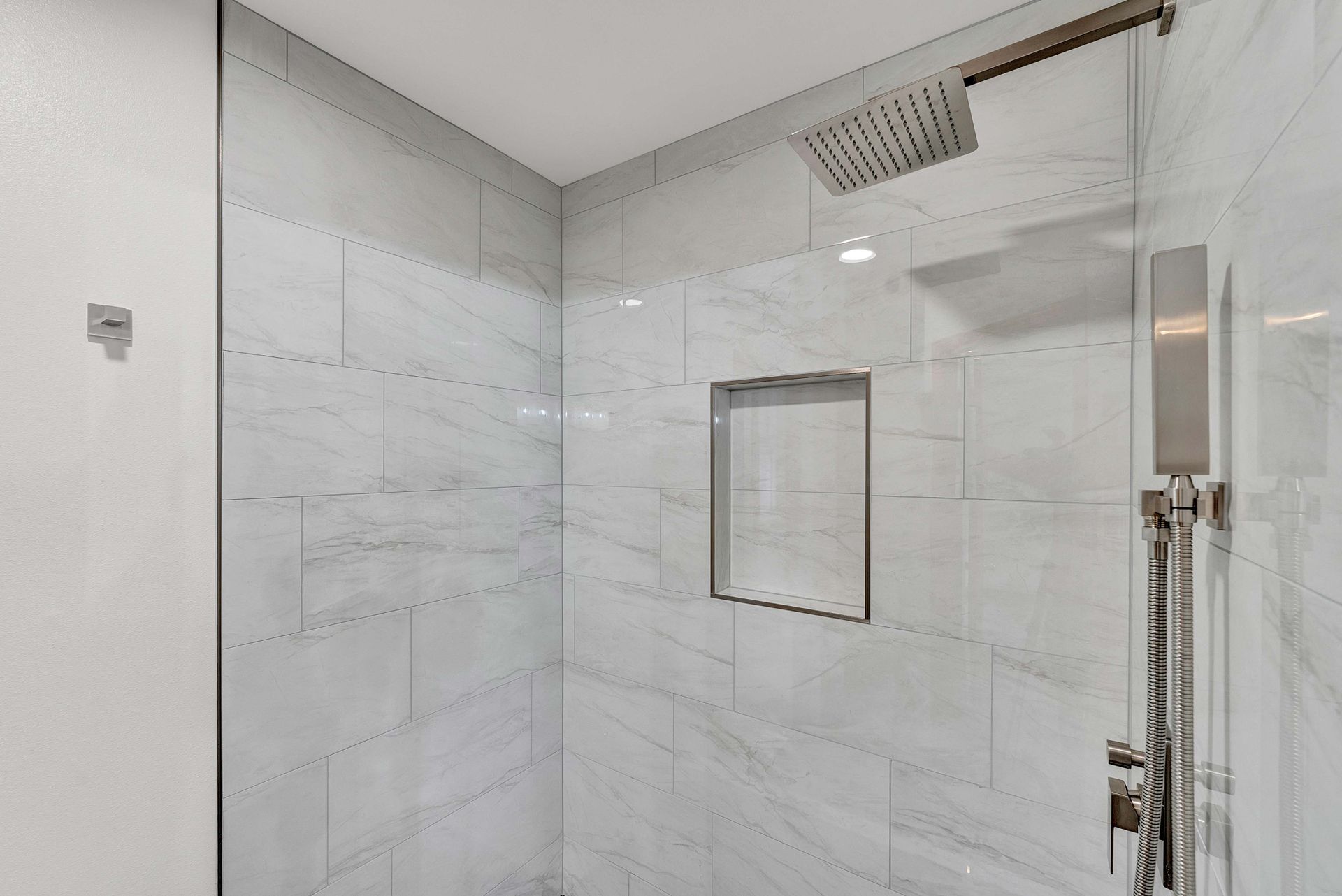 A bathroom with a walk in shower and a shower head.