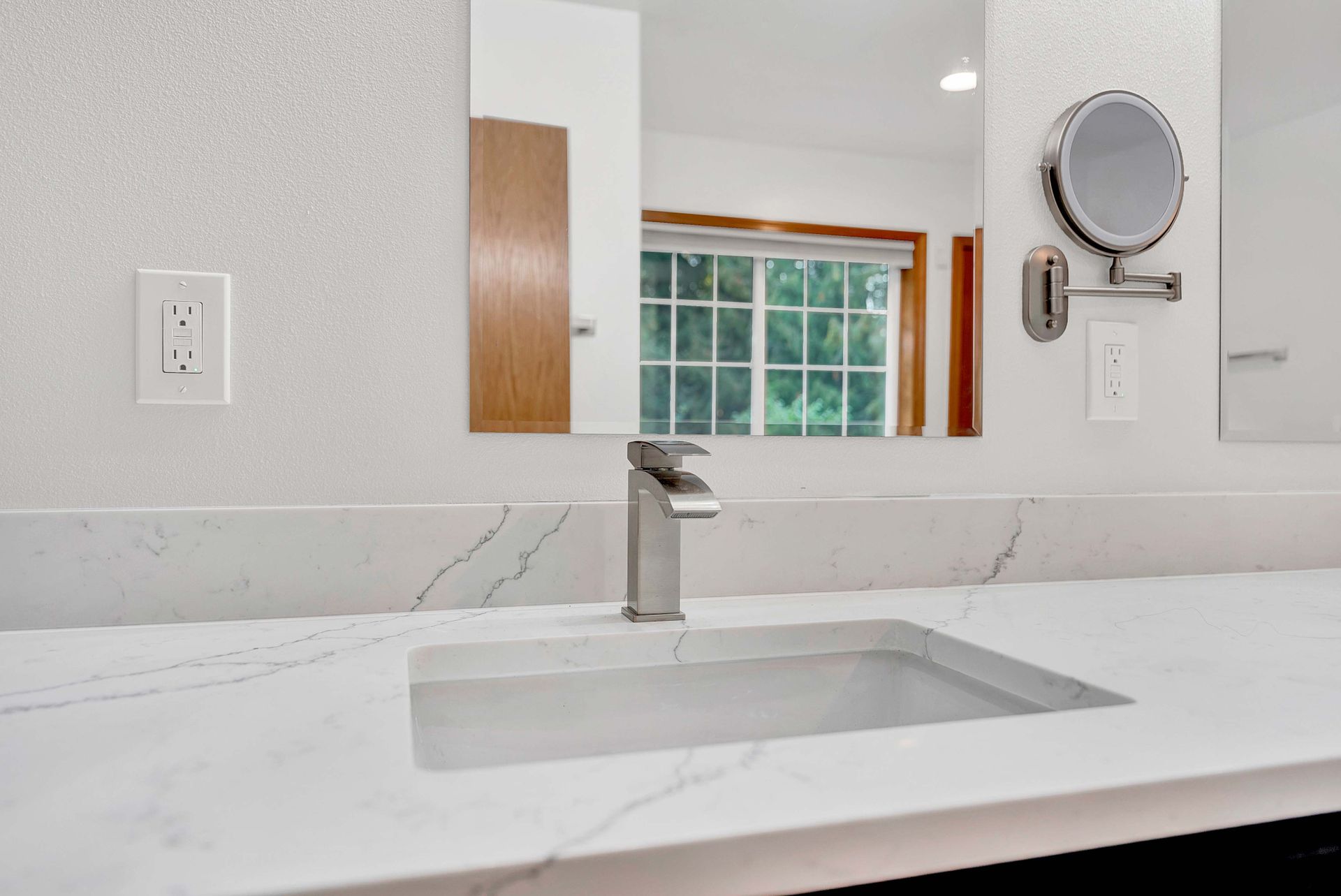 A bathroom with a sink , mirror and faucet.