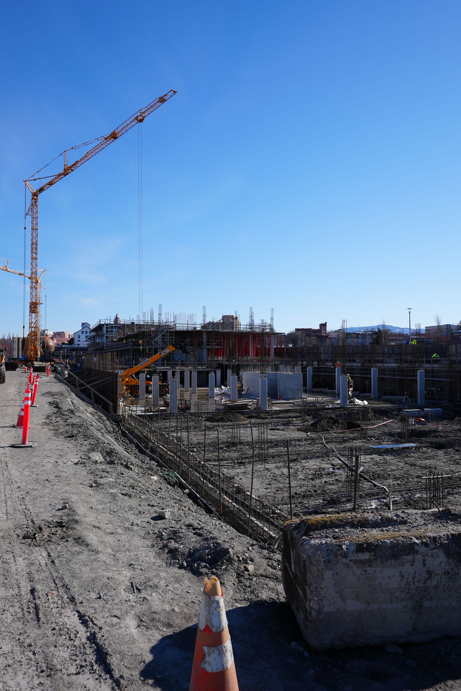 A construction site with a crane and cones in the foreground.