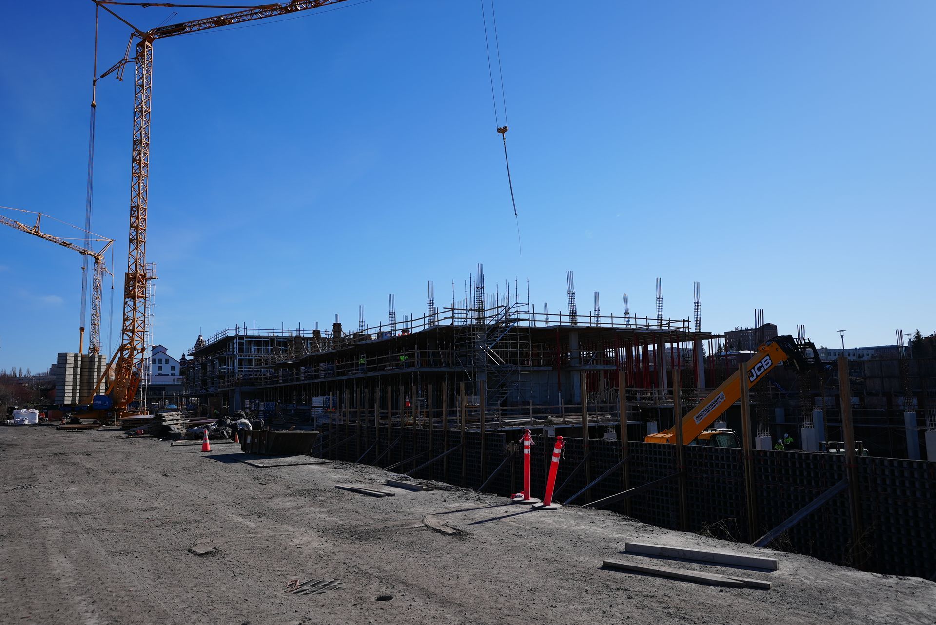 A construction site with a lot of cranes and a blue sky in the background.