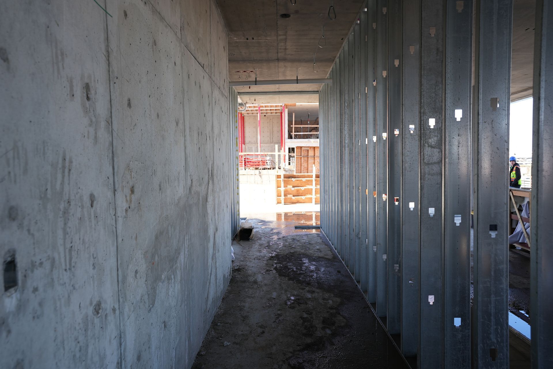 A hallway in a building under construction with a concrete wall and metal walls.
