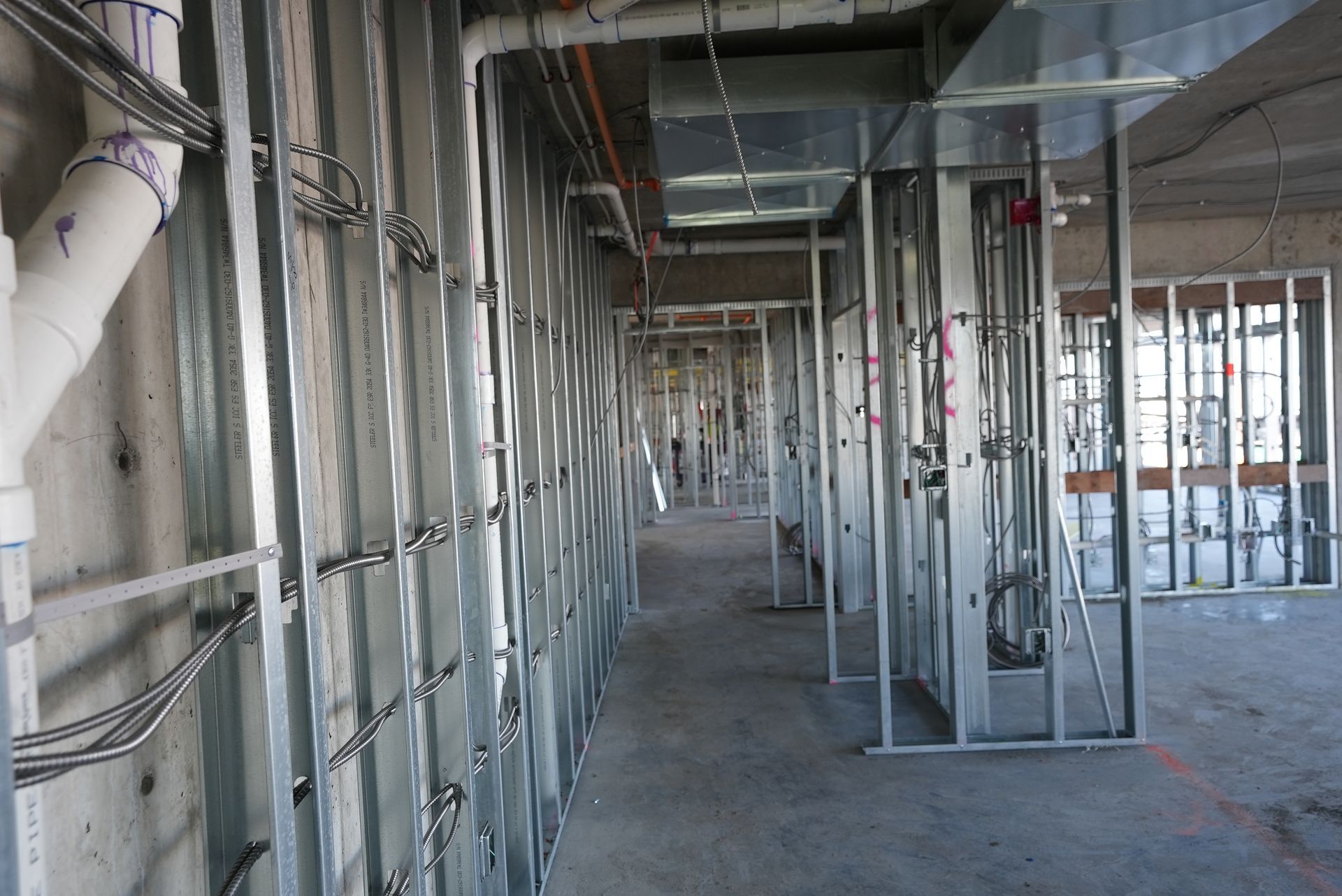 A long hallway in a building under construction with pipes and wires