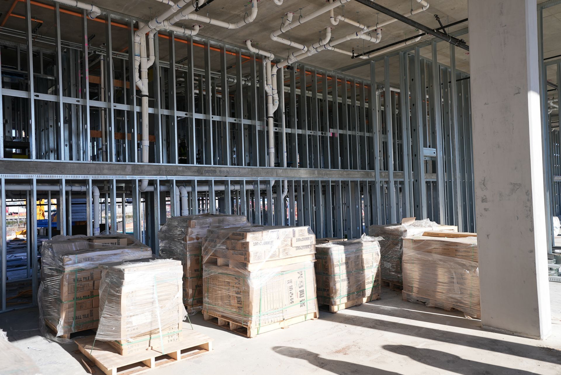 A building under construction with pallets of bricks and pipes.