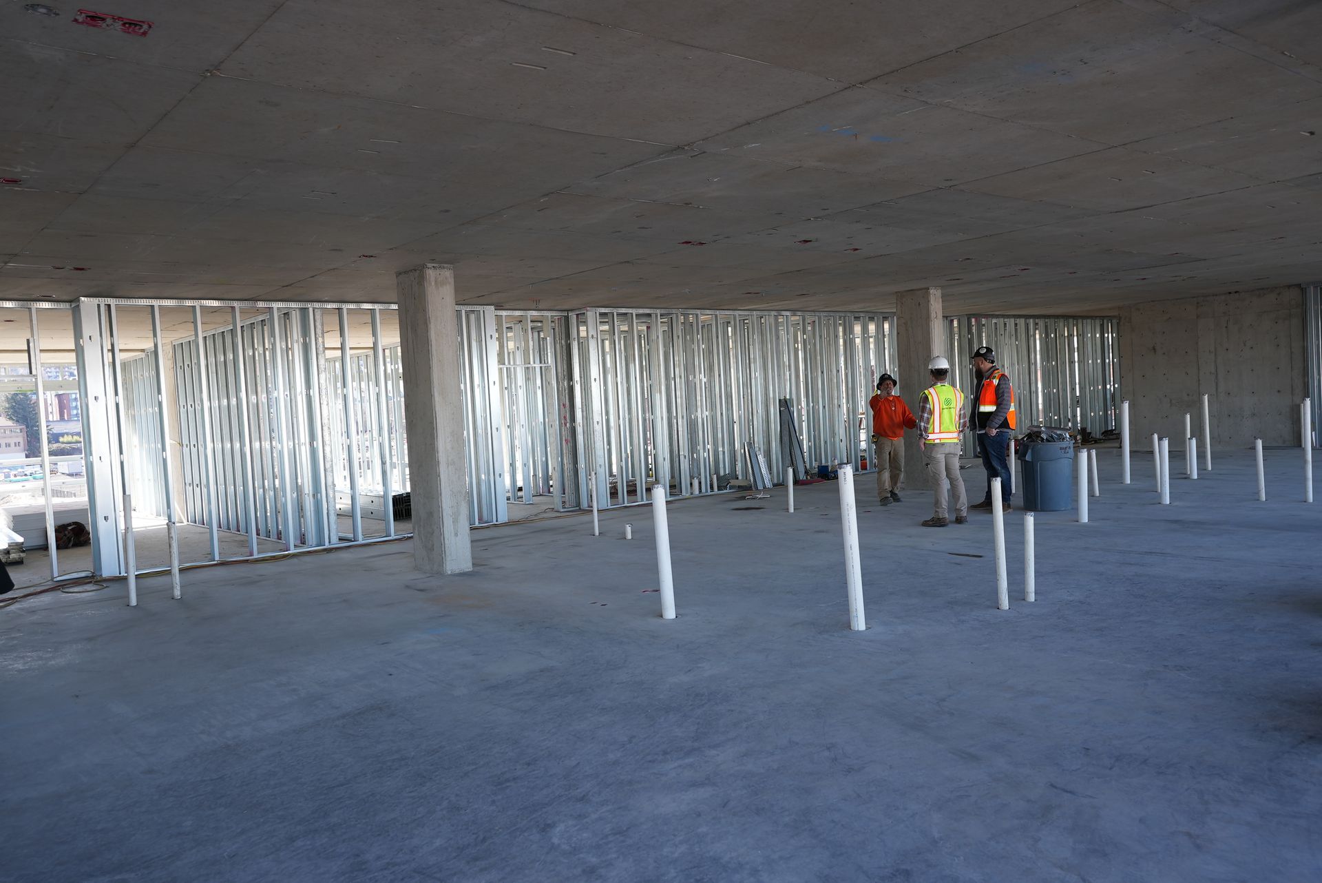 A group of construction workers are standing in a building under construction.