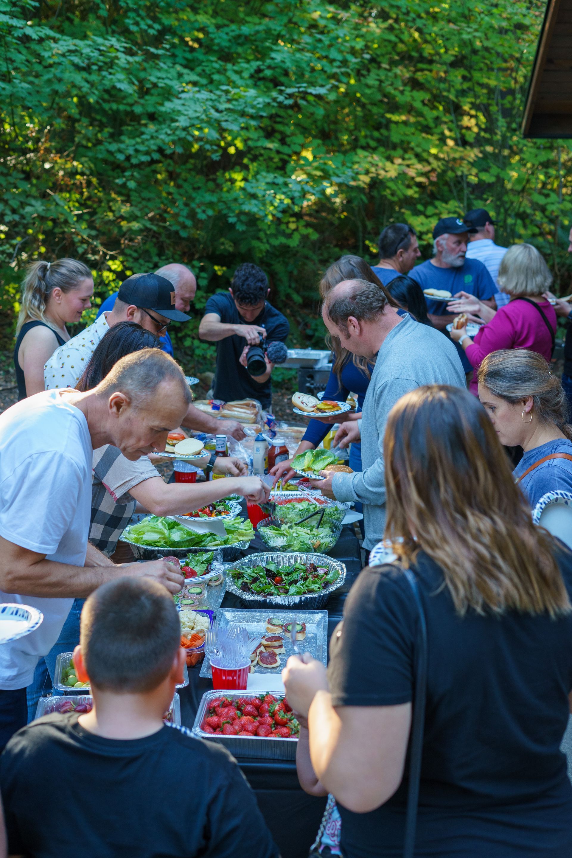 A large group of people are standing around a table eating food.