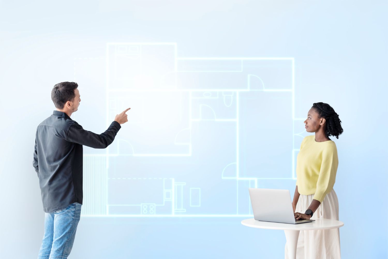 A man and a woman are standing next to each other in front of a blueprint of a house.