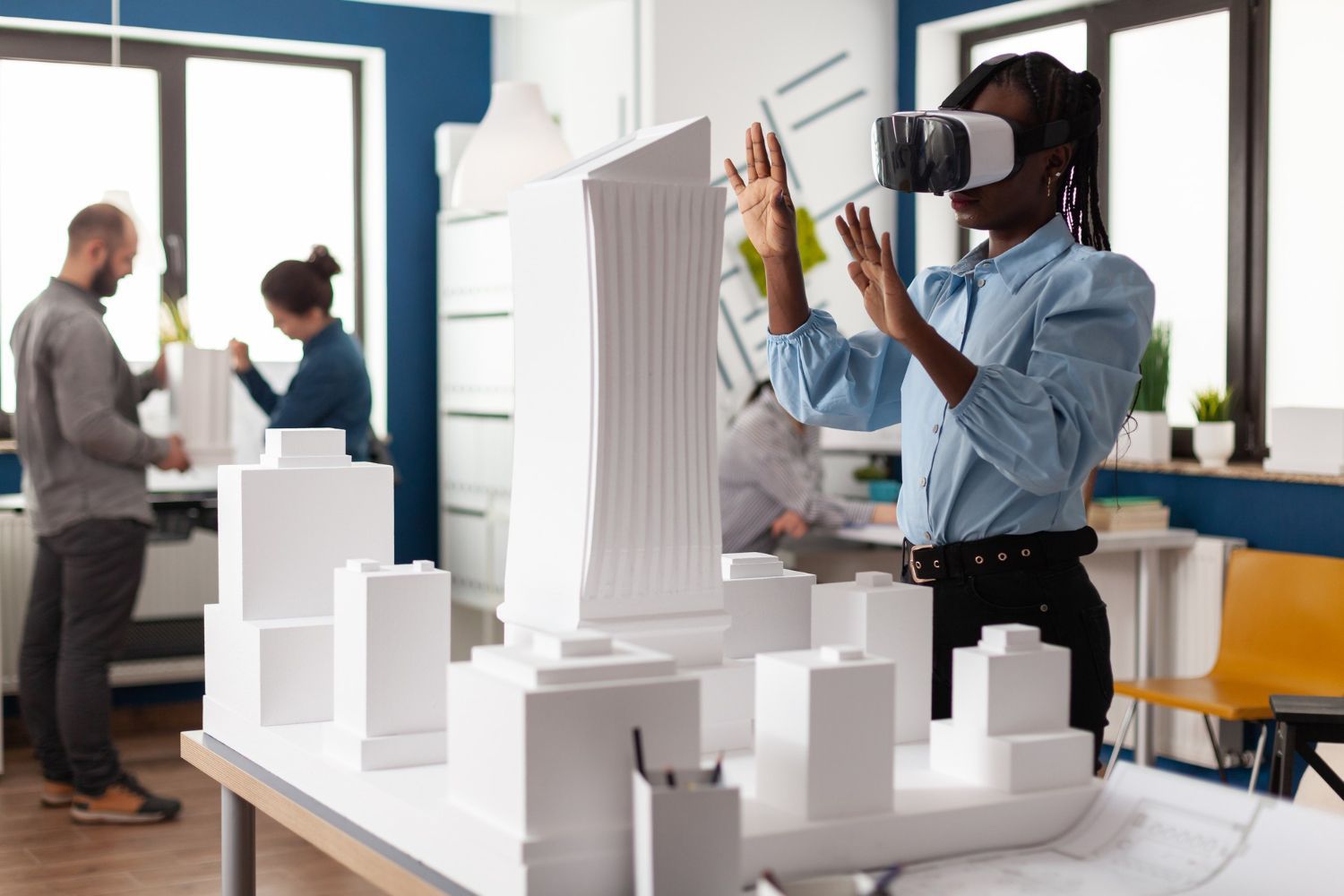 A woman is wearing a virtual reality headset while looking at a model of a city.