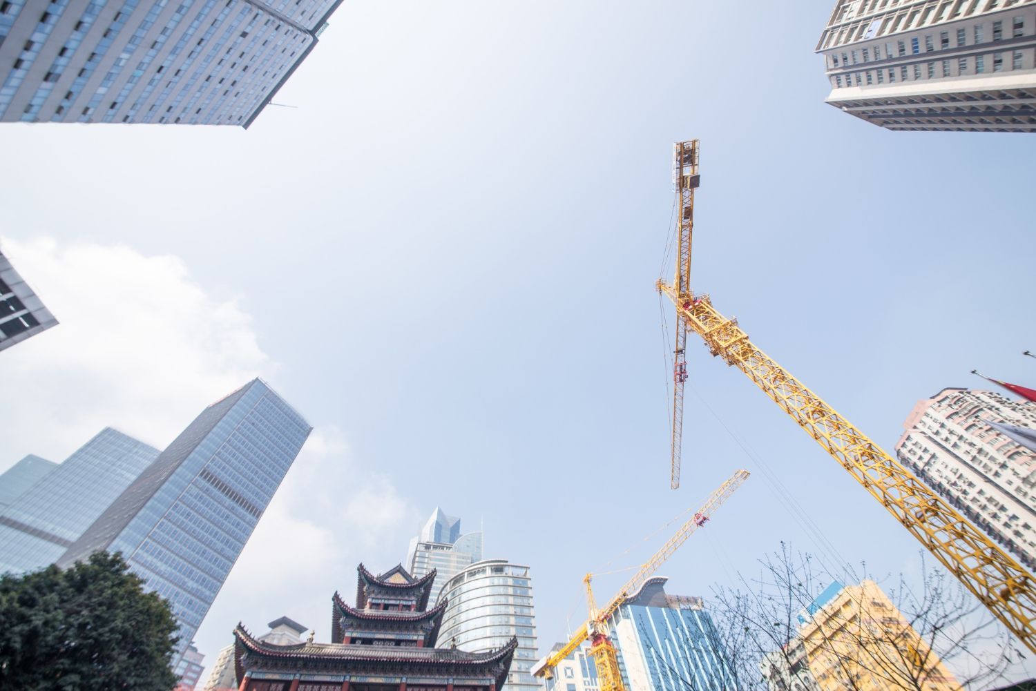 Looking up at a building under construction with a crane in the foreground.
