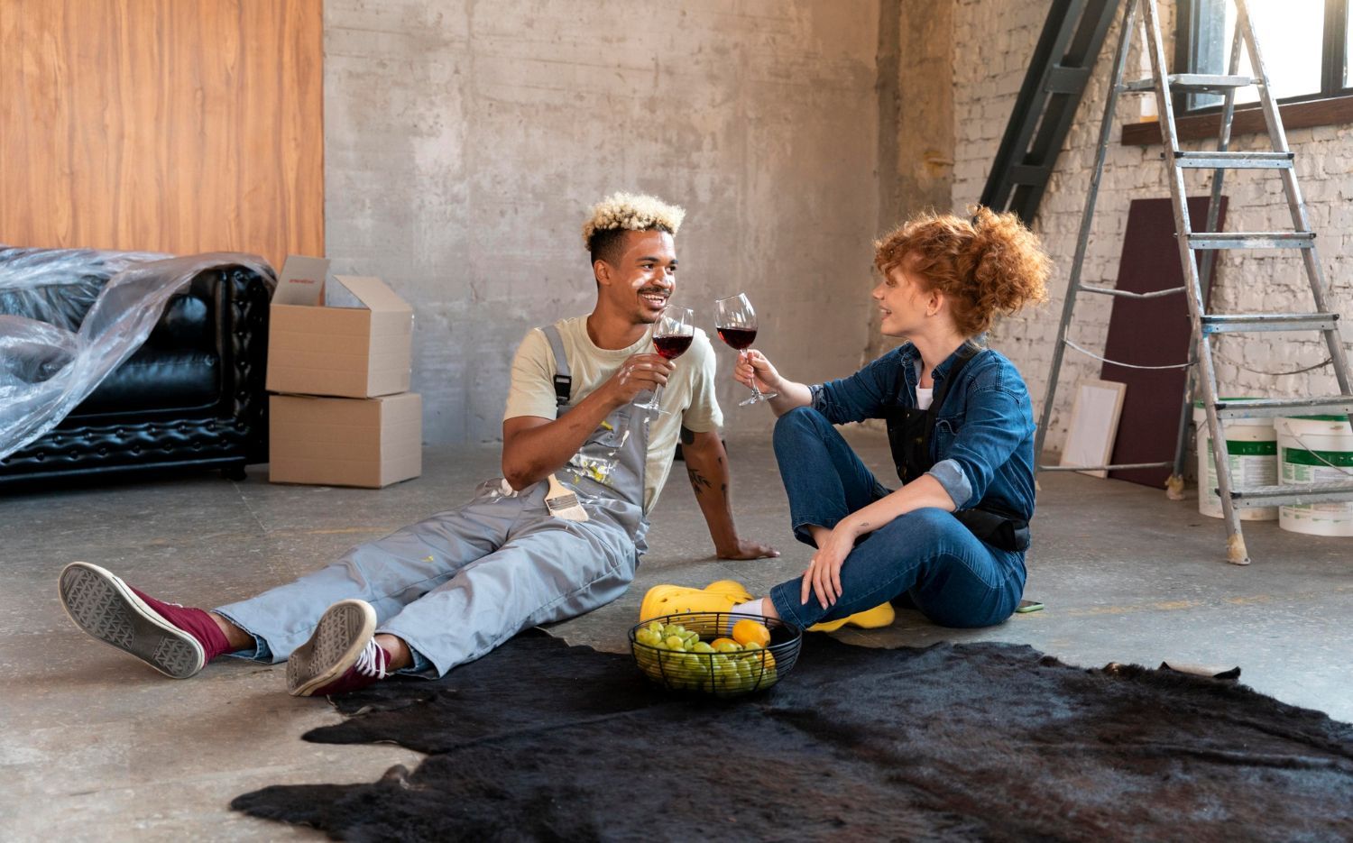 A man and a woman are sitting on the floor drinking wine.