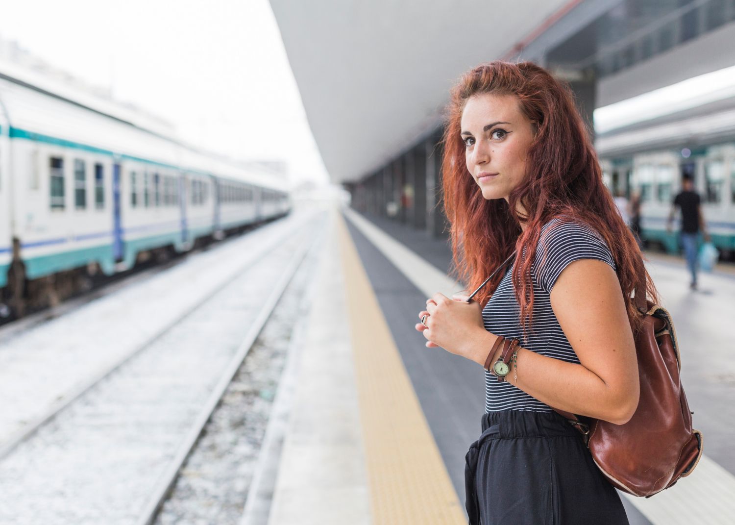 A woman is waiting for a train at a train station.