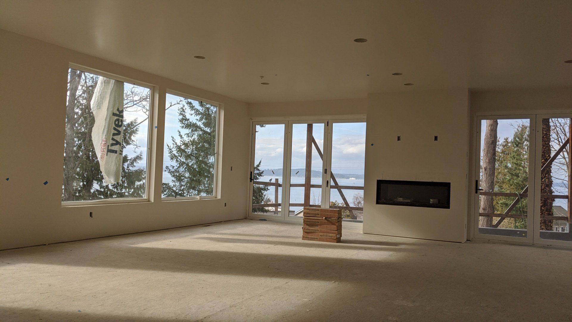 A large empty room with a fireplace and lots of windows