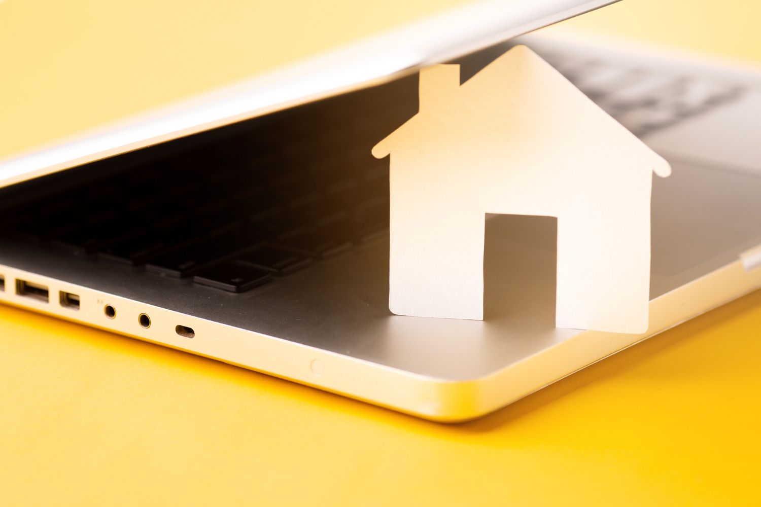 A paper house is sitting on top of a laptop computer.