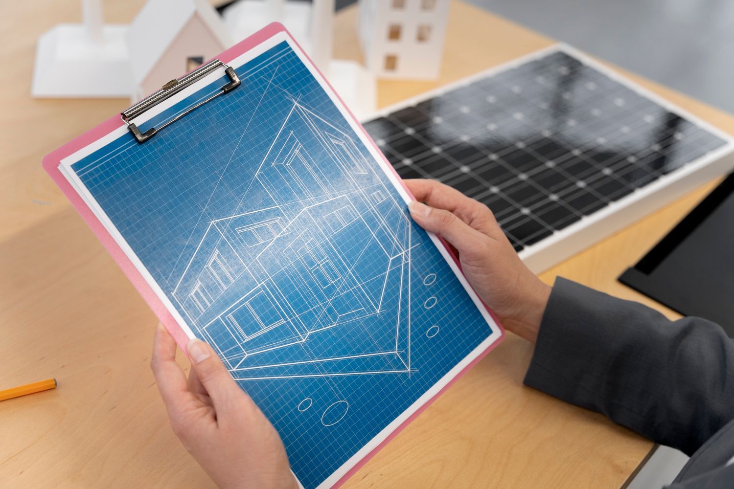 A person is holding a clipboard with a drawing of a house on it.