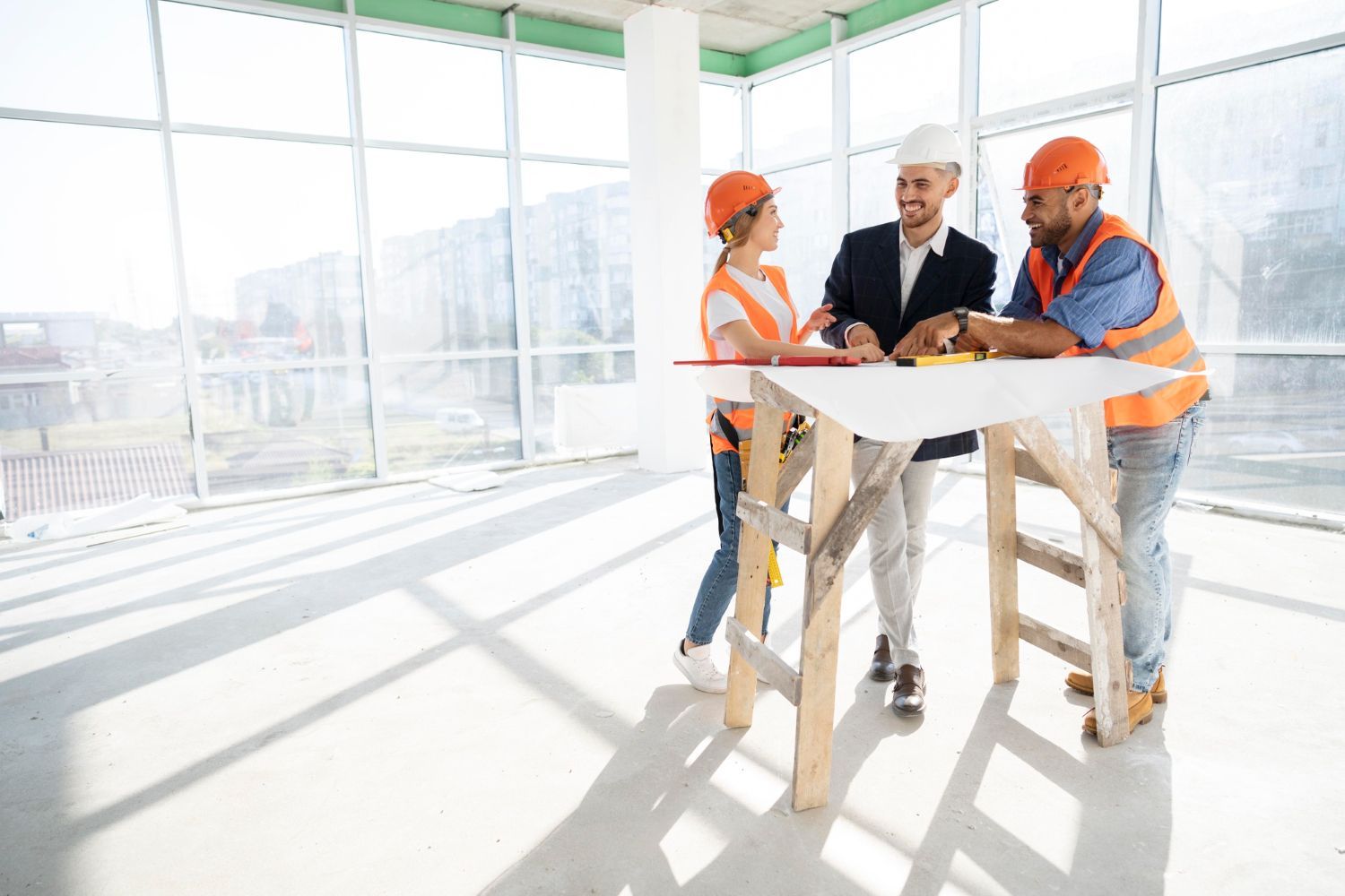A group of construction workers are standing around a table at a construction site.