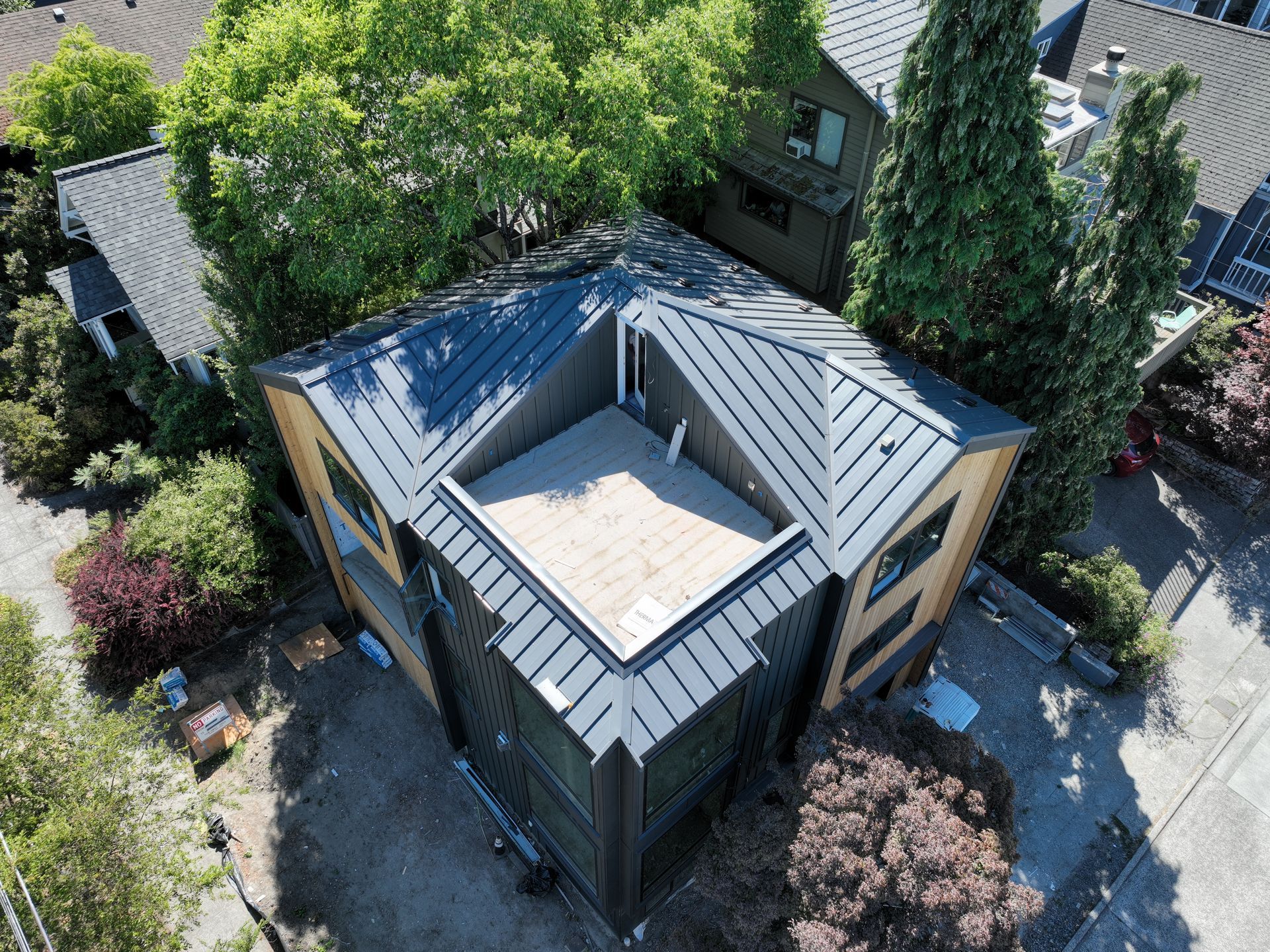 An aerial view of a house with a roof that is surrounded by trees.