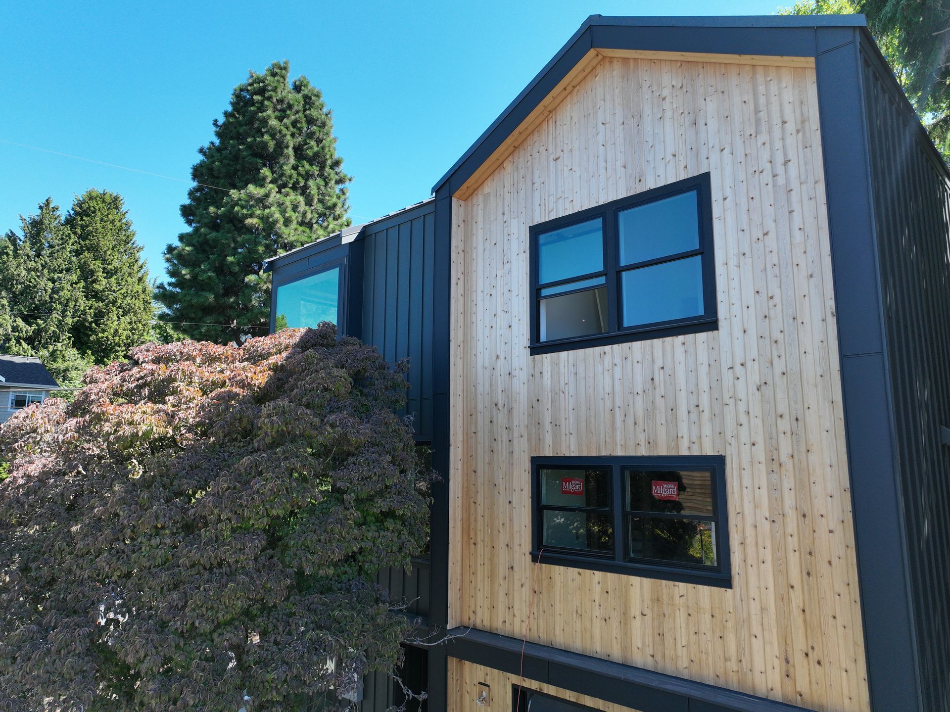 A wooden house with a black roof and a lot of windows