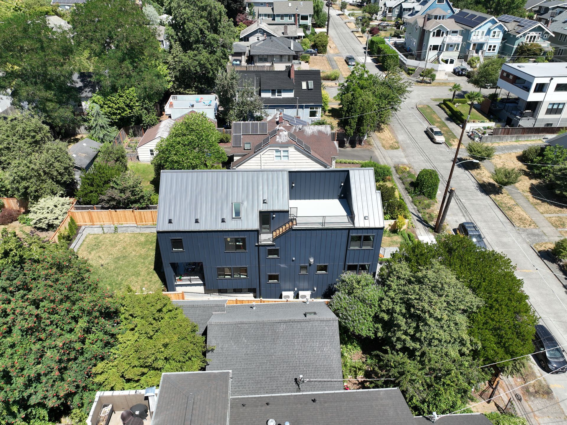 An aerial view of a house in a residential area surrounded by trees.