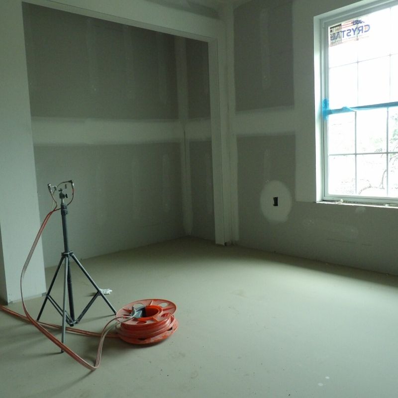 An empty room with a window and a tape measure on the floor