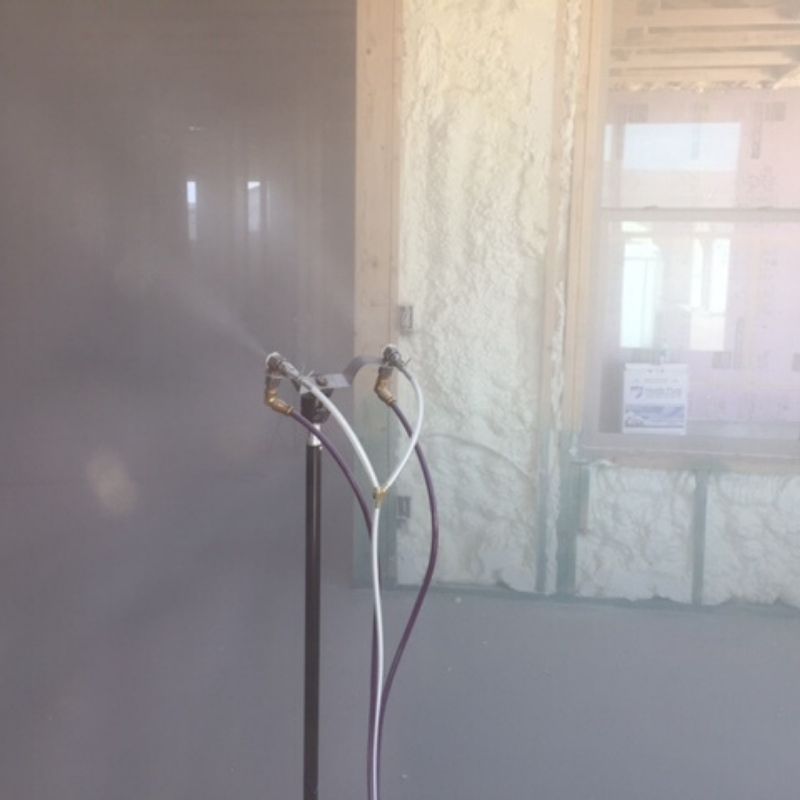 Two microphones are sitting in a room with a gray wall.