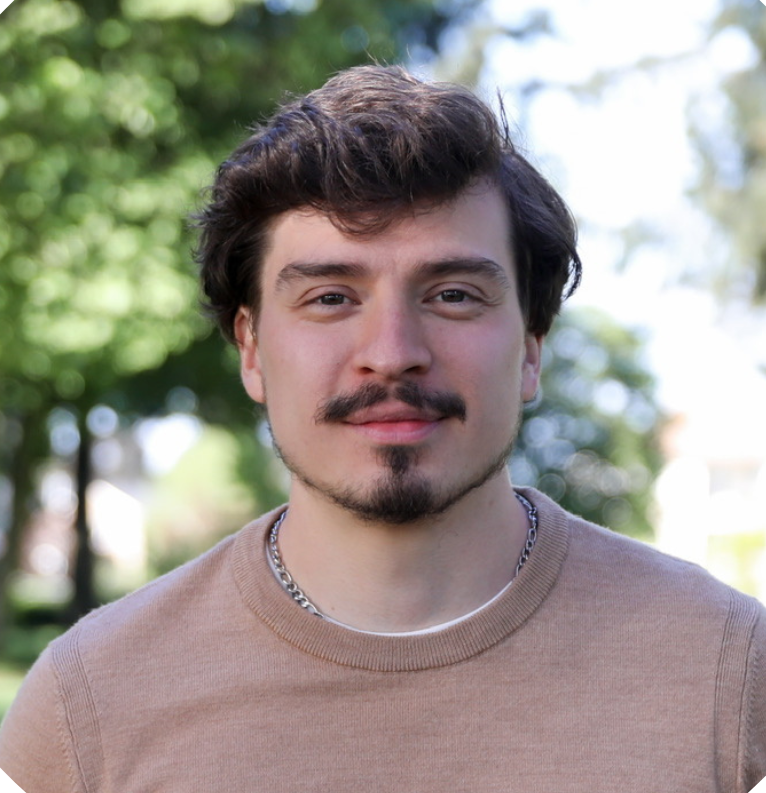 A man in a plaid shirt is standing in front of a tree.