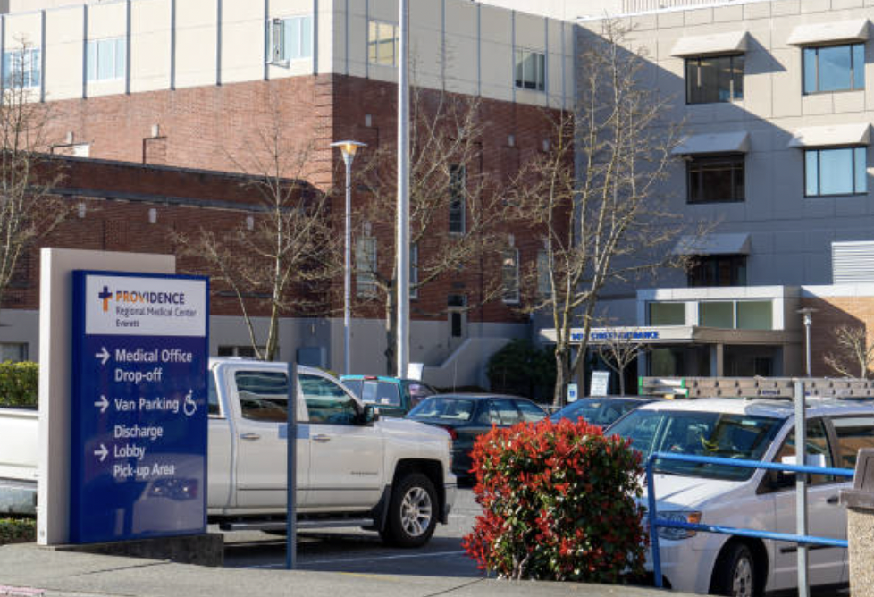 A white truck is parked in front of a hospital.