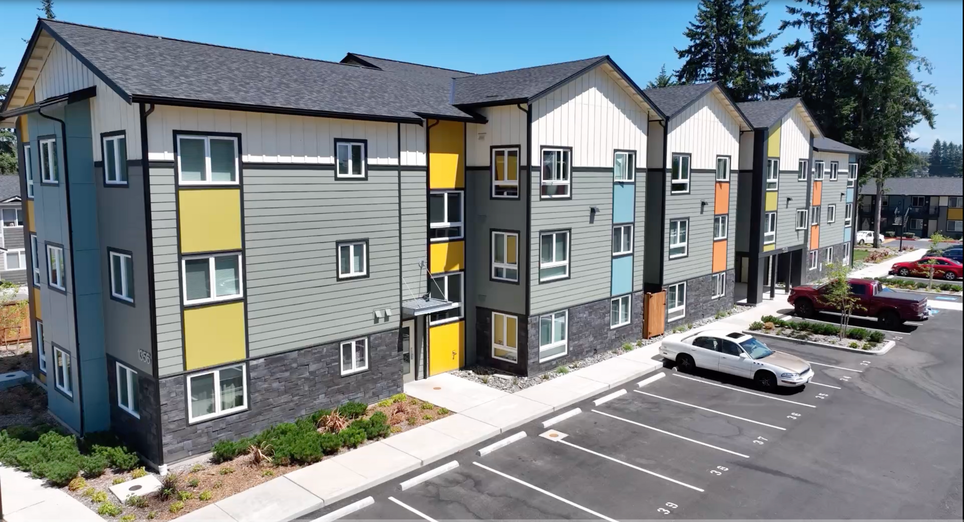A large apartment building with cars parked in front of it.