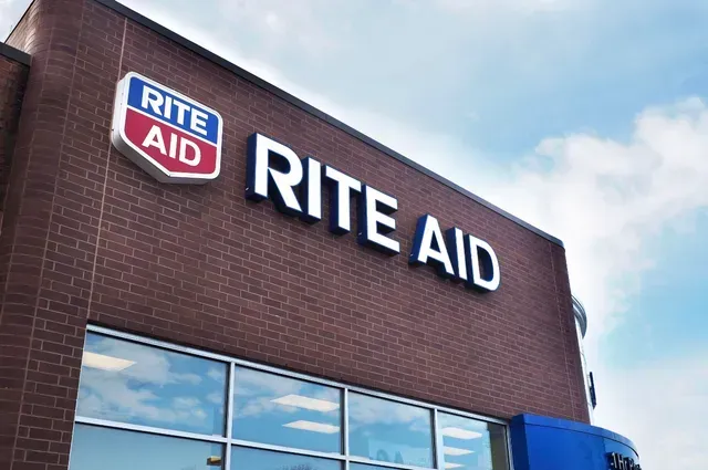 The front of a rite aid store against a blue sky.