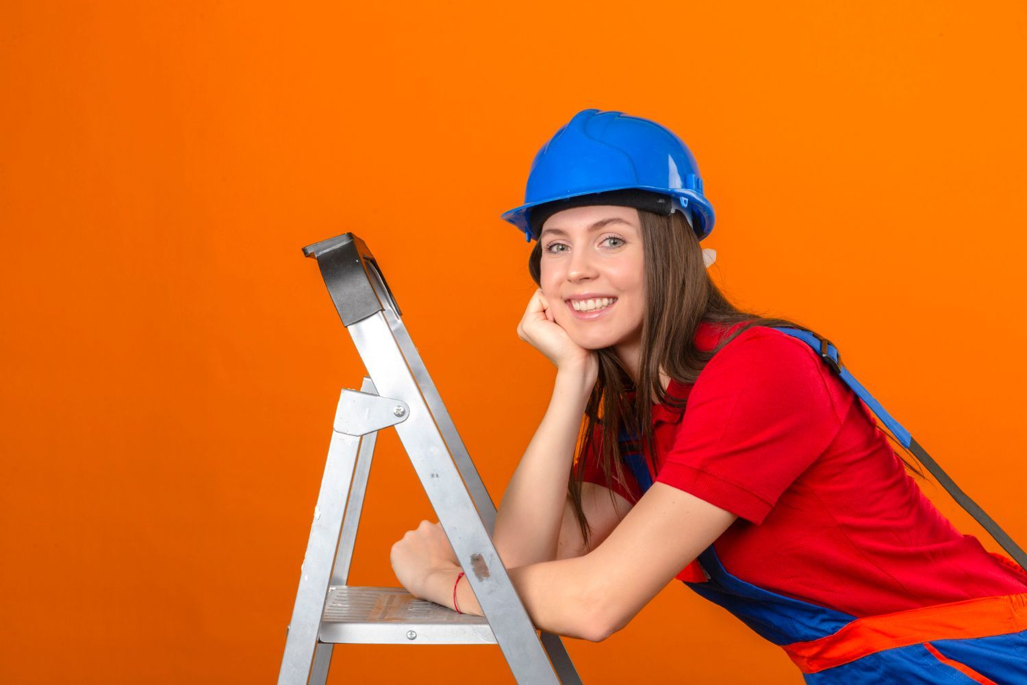 A woman wearing a hard hat is leaning on a ladder.