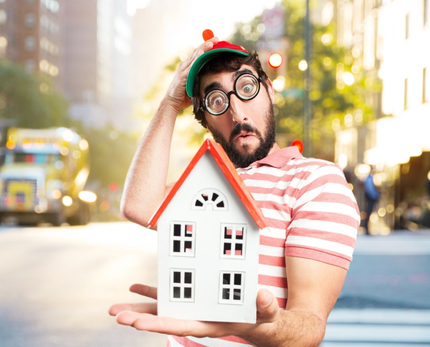A man is holding a small model house in his hand.
