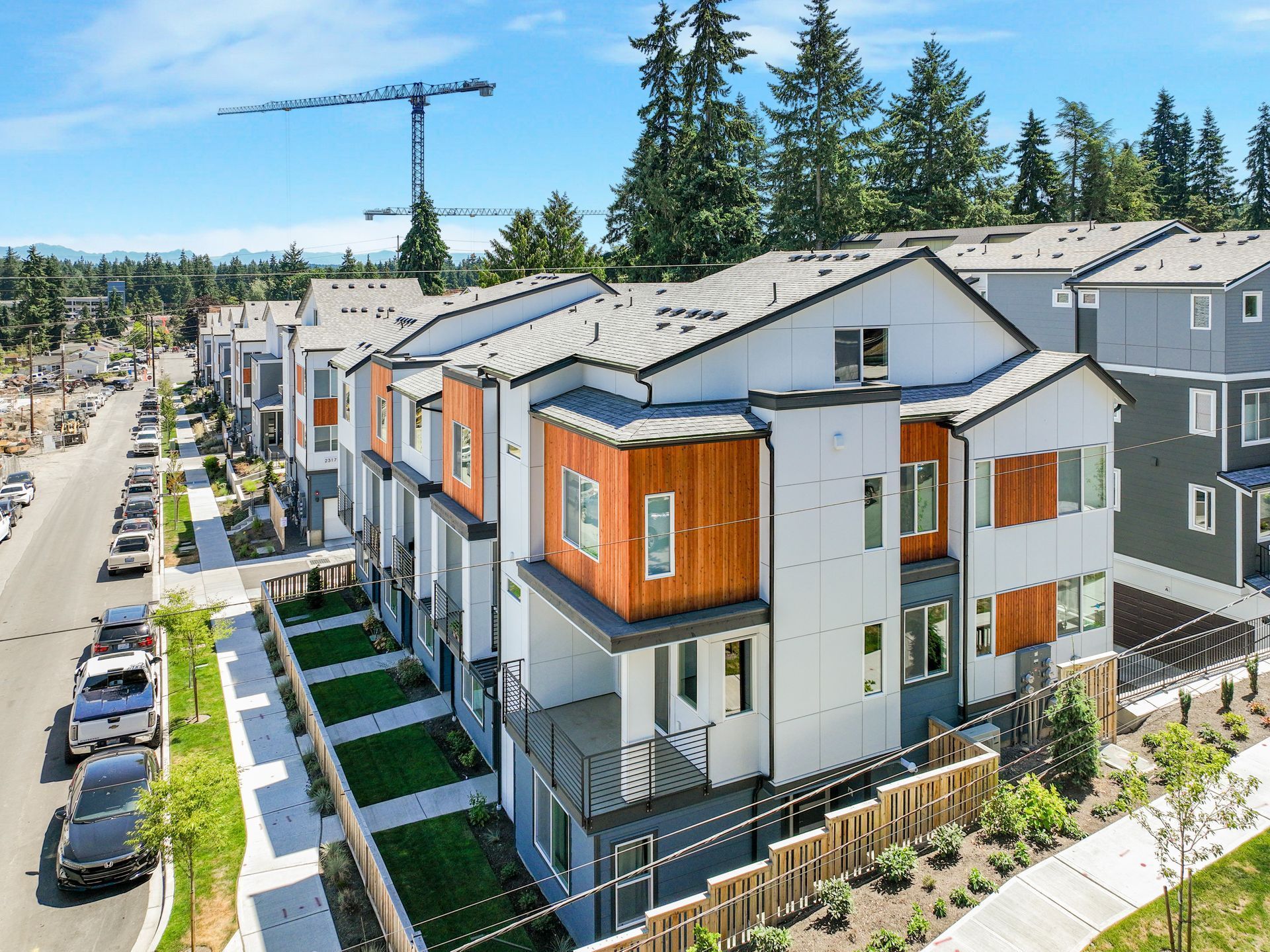 An aerial view of a row of apartment buildings with cars parked in front of them.