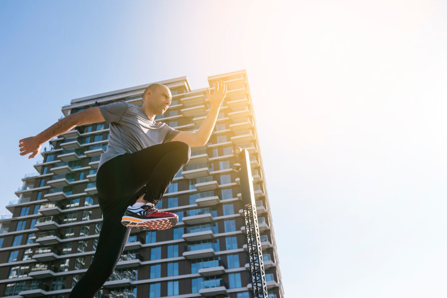 A man is jumping in the air in front of a tall building.