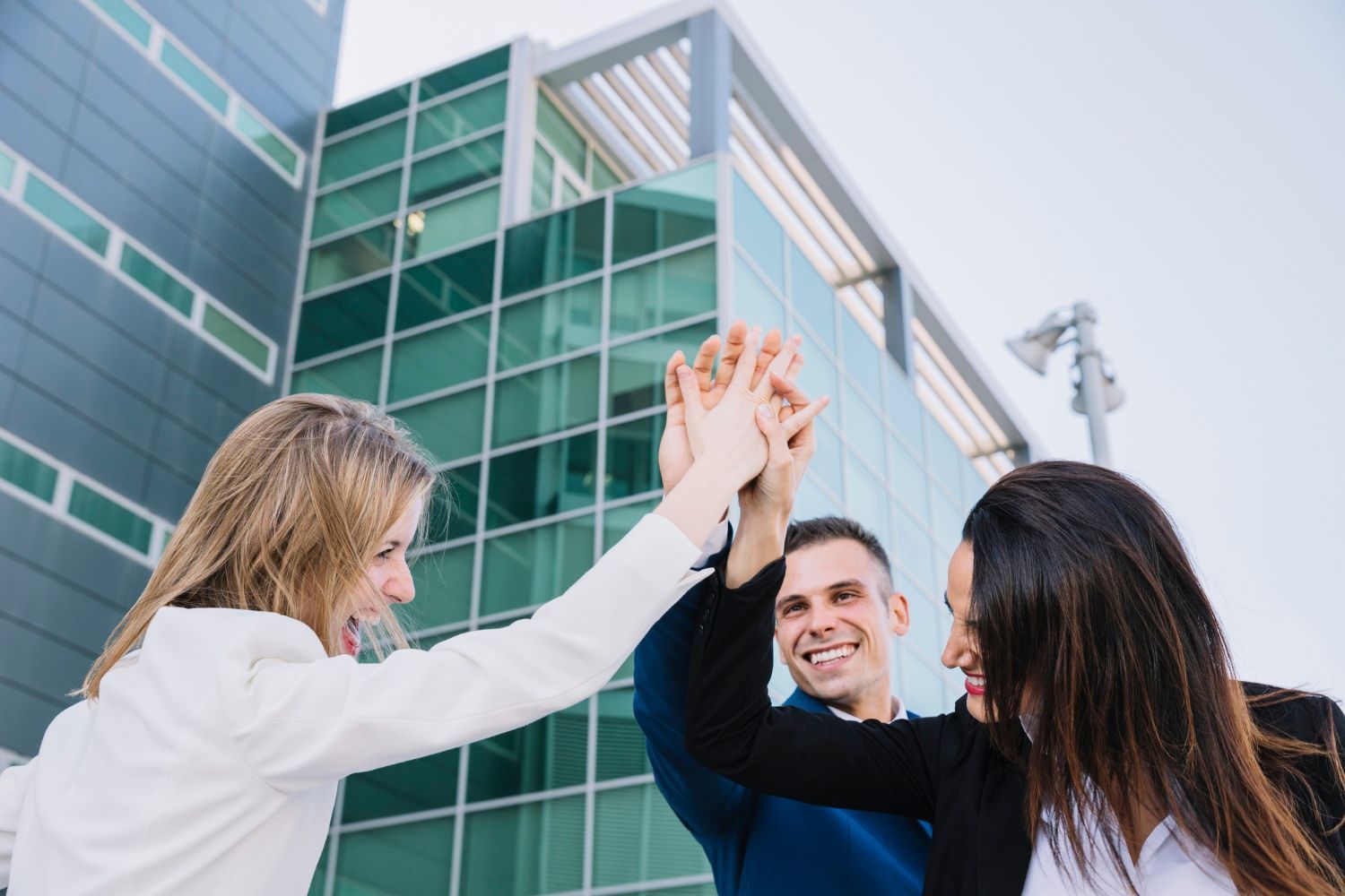 A group of people are giving each other a high five in front of a building.