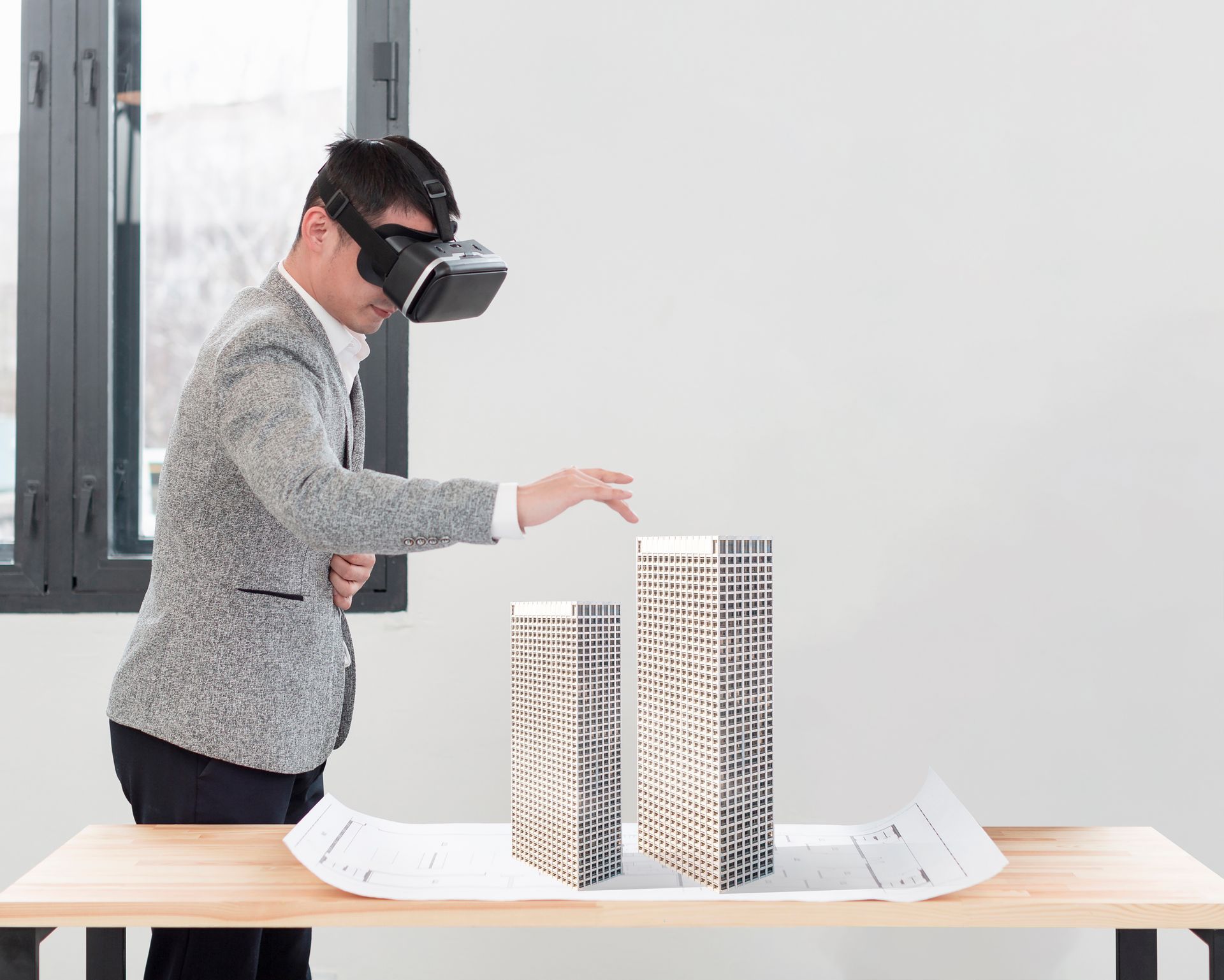 A man wearing a virtual reality headset is playing with a model of a building.