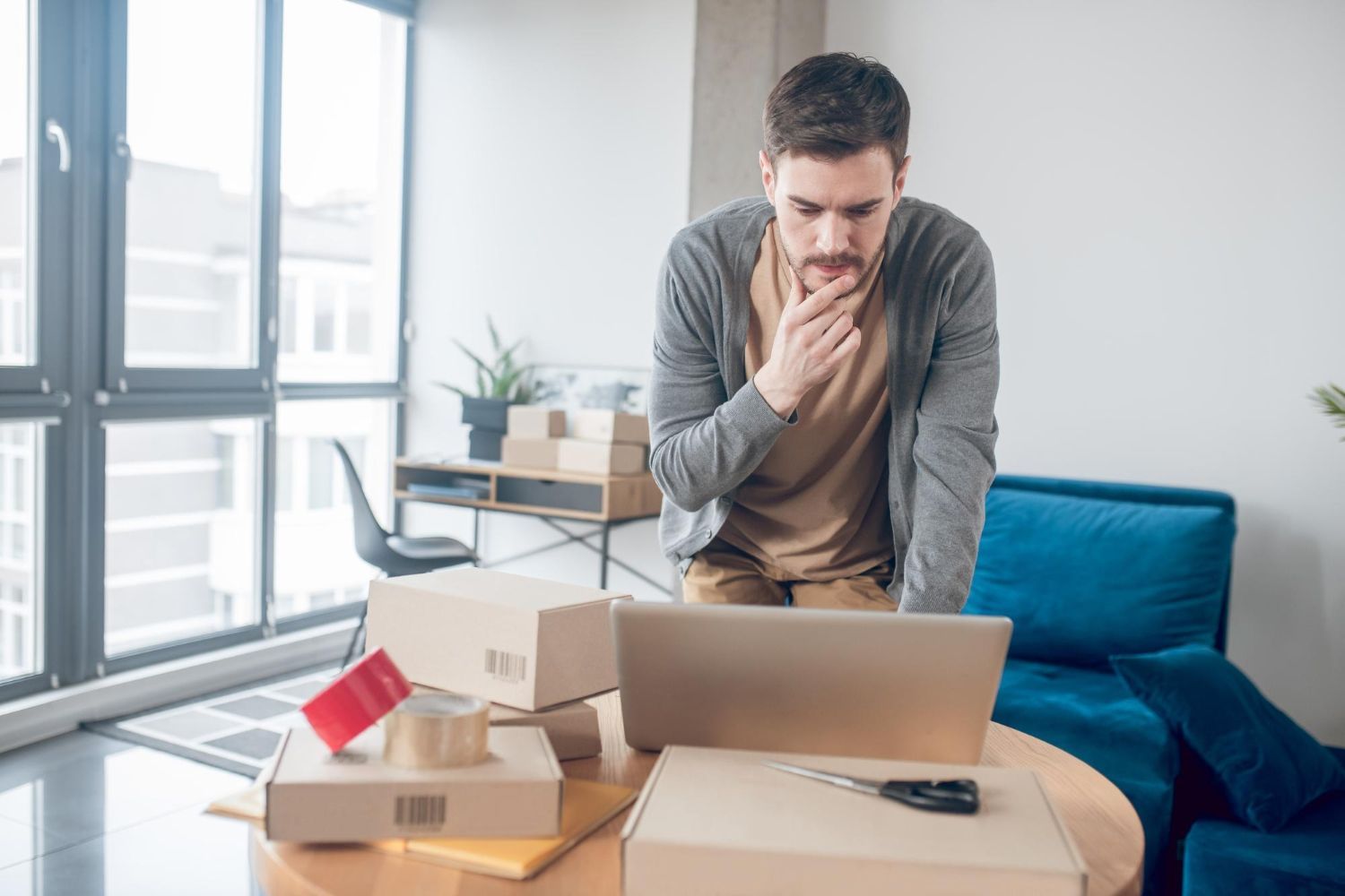 A man is sitting at a table with boxes and a laptop.
