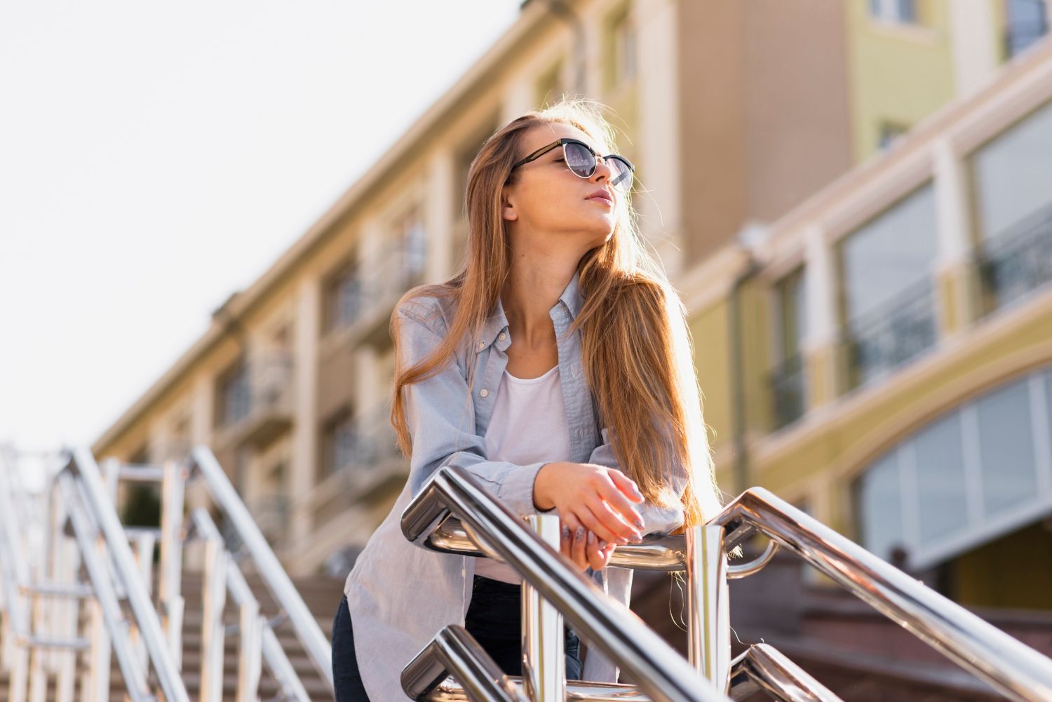A woman wearing sunglasses is standing on a set of stairs.