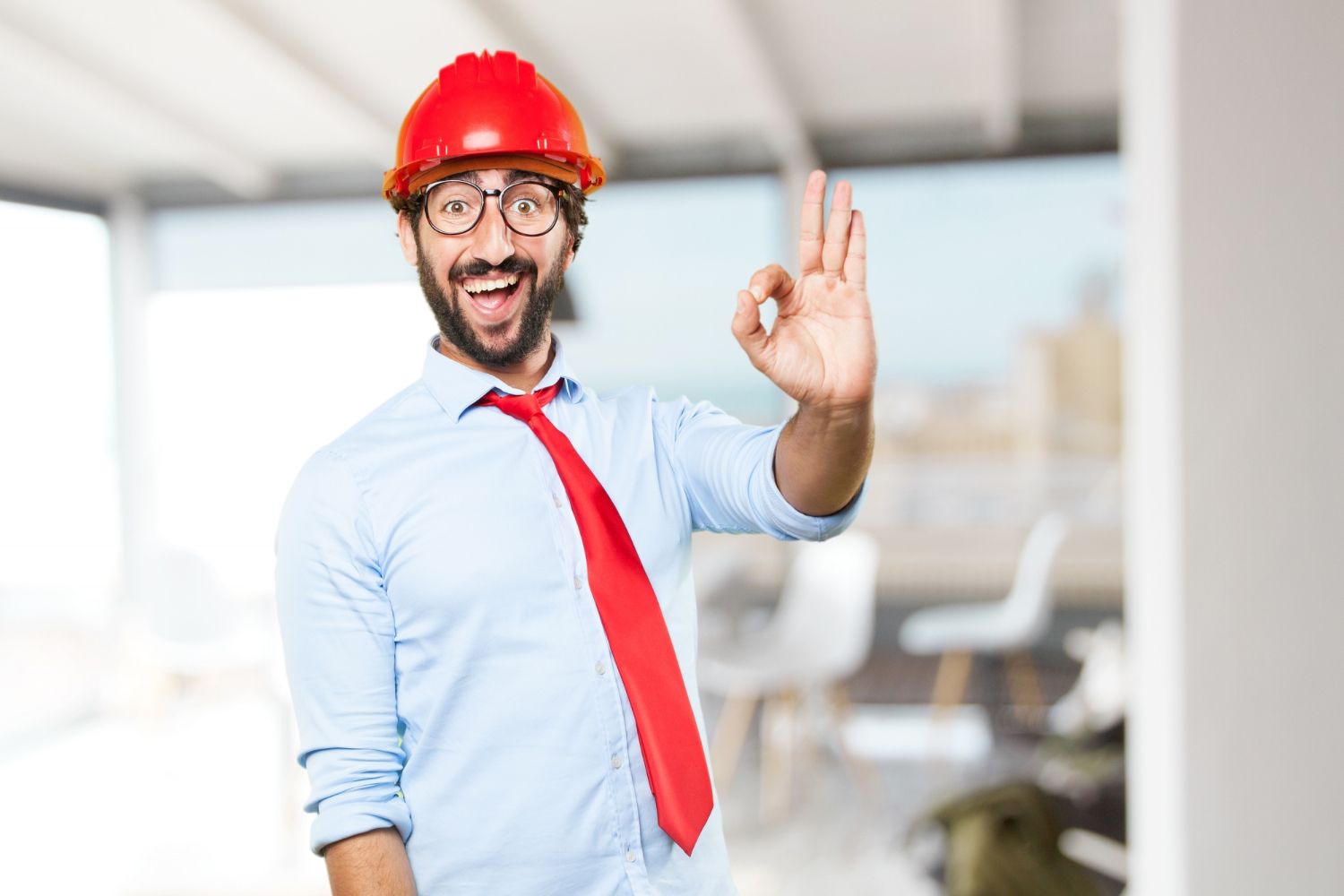A man wearing a hard hat and tie is giving an ok sign.