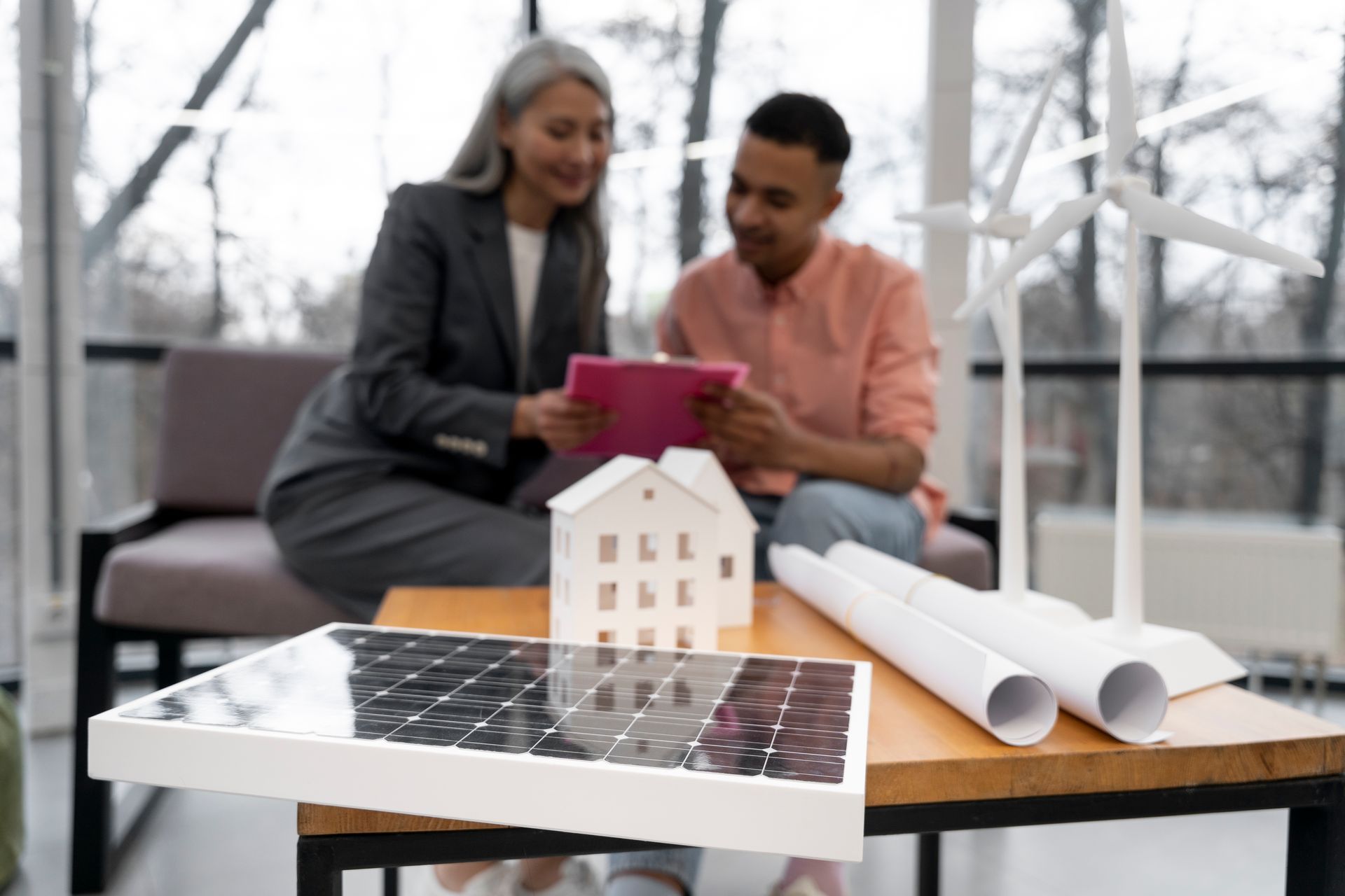 A man and a woman are sitting at a table looking at a tablet.