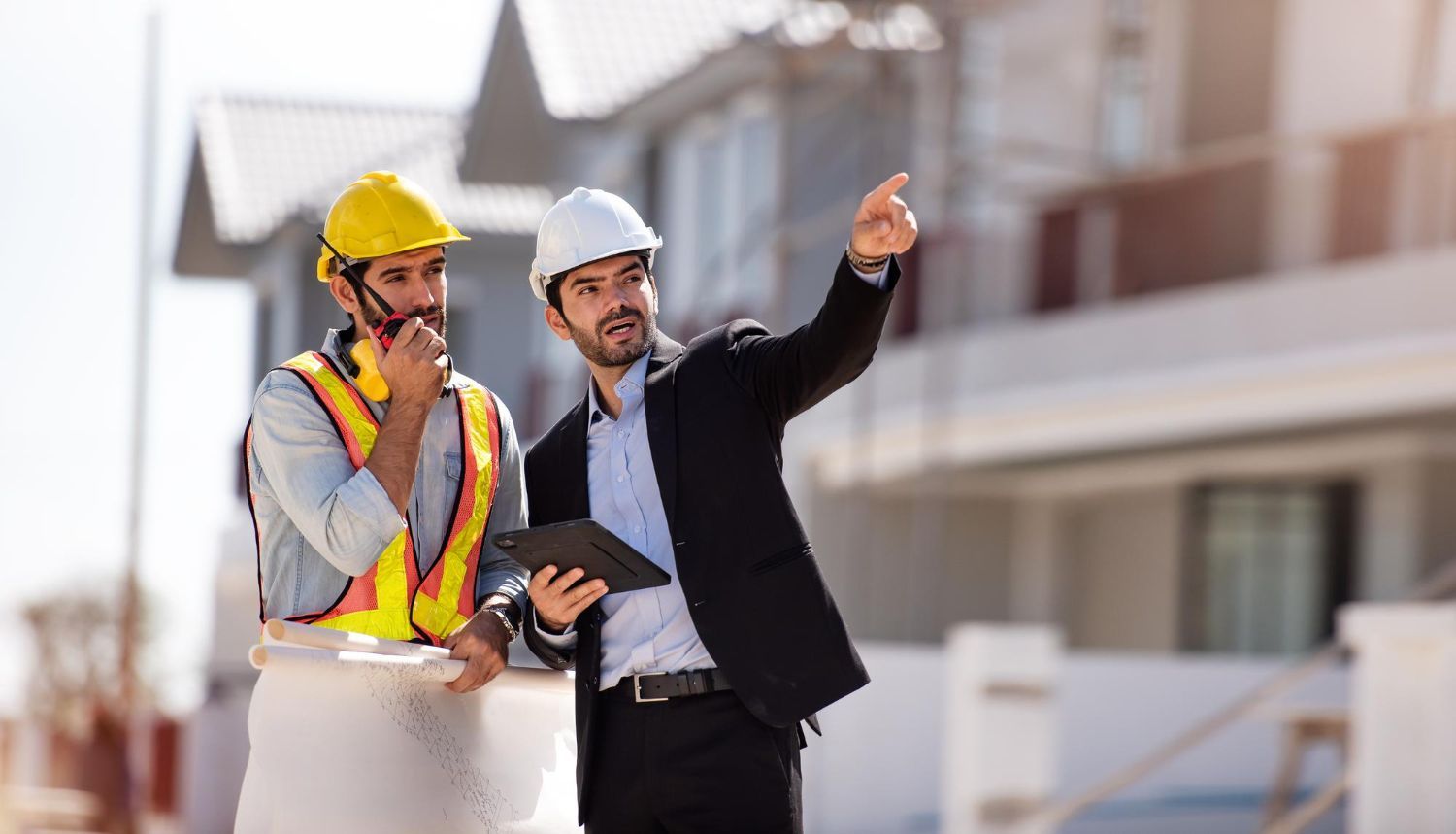 Two construction workers are standing next to each other on a construction site.