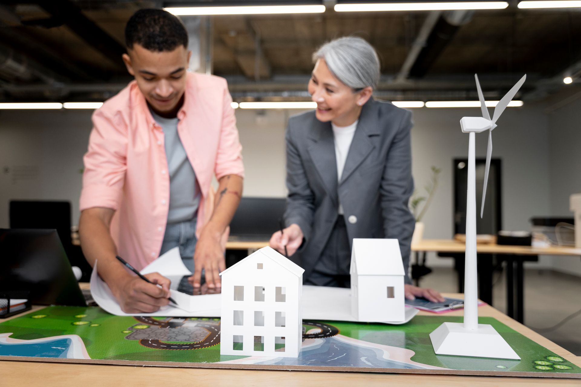 A man and a woman are looking at a model of a house and windmill.