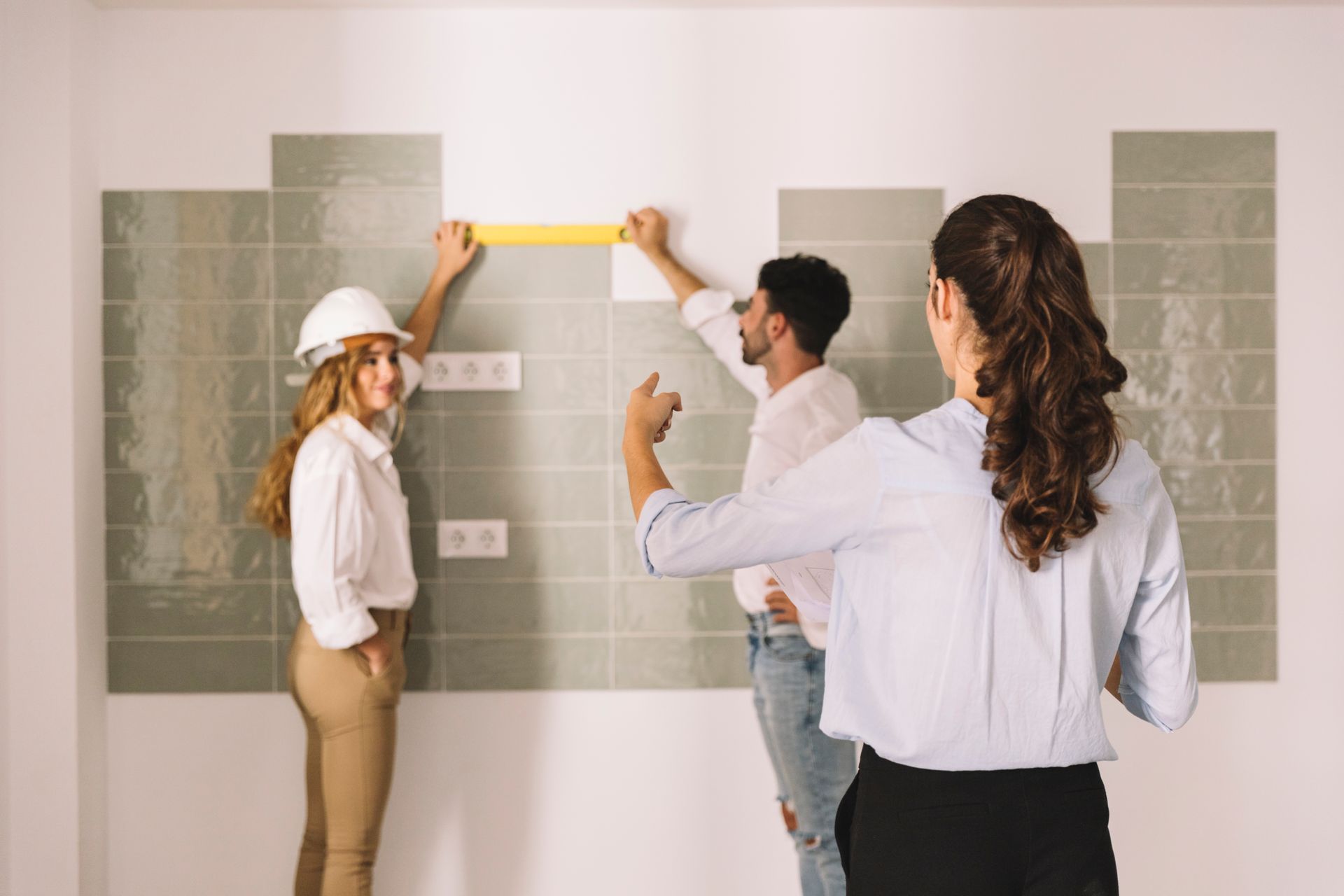 A group of people are measuring a wall with a tape measure.