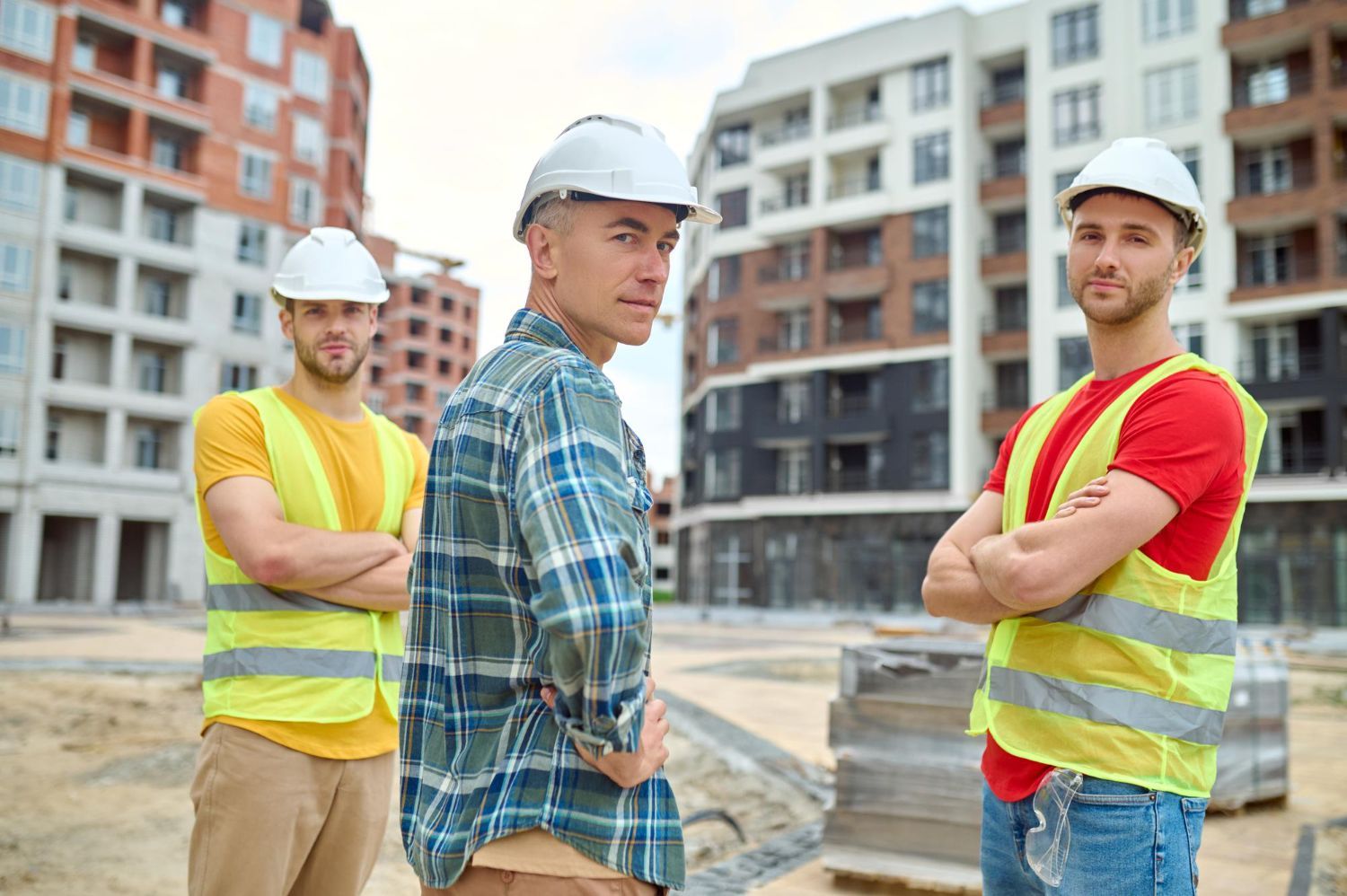 Three construction workers are standing next to each other on a construction site.
