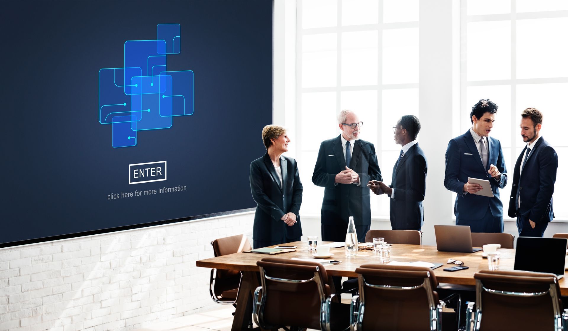 A group of business people are standing around a conference table in a conference room.