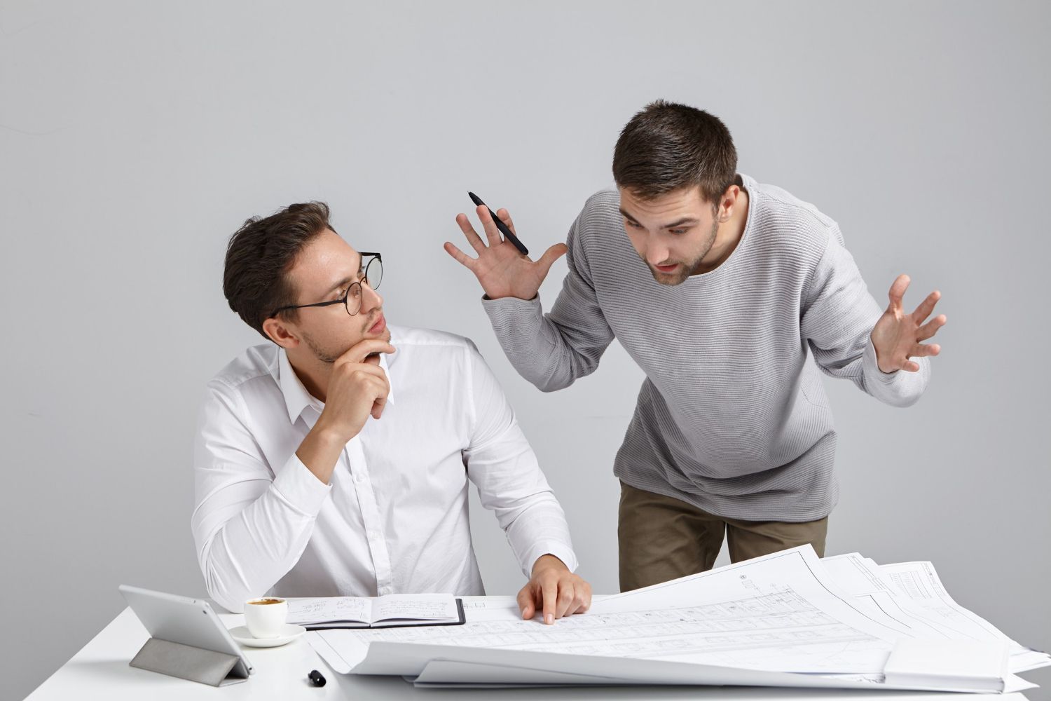 Two men are standing next to each other at a table.