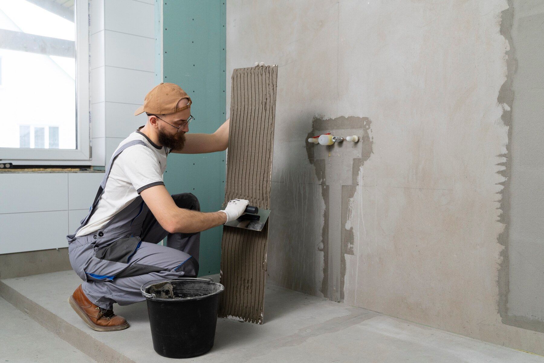 A man is plastering a wall in a bathroom.