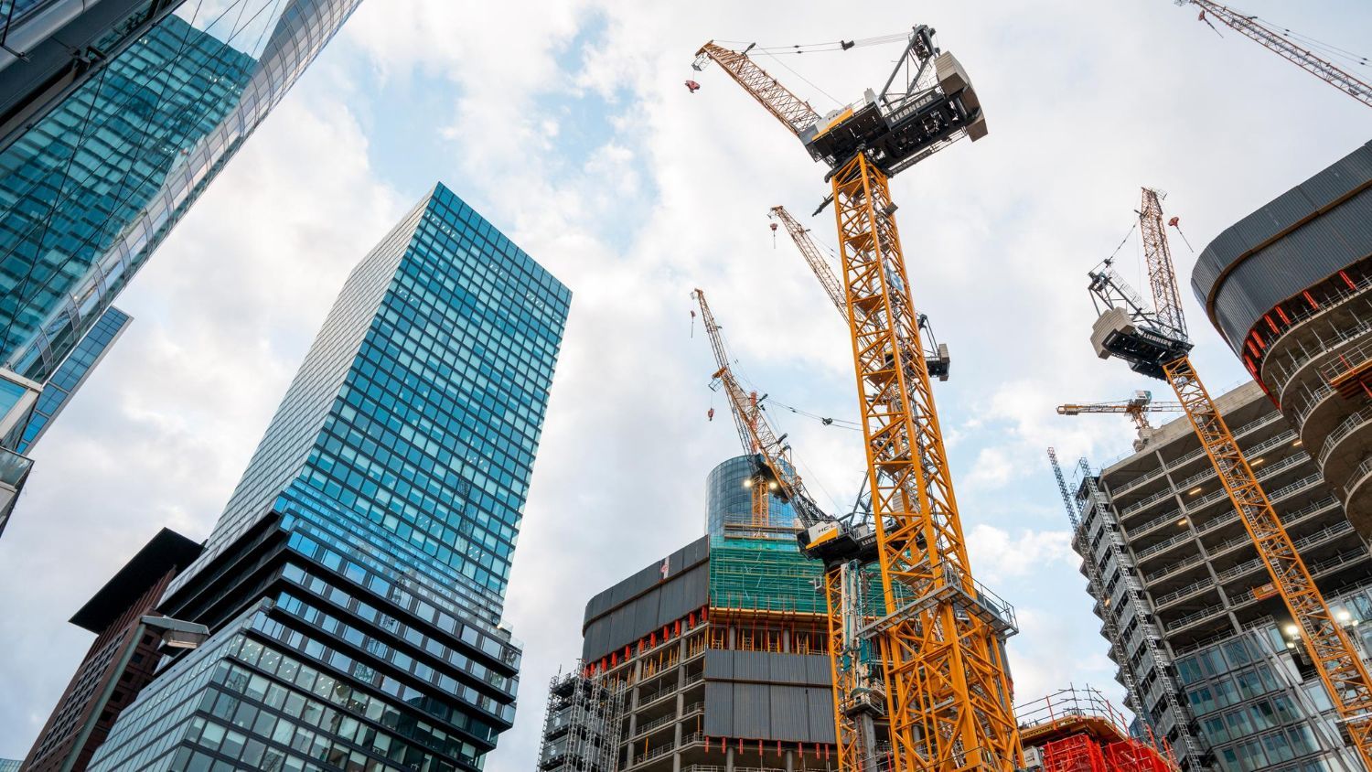 A construction site with a lot of cranes and buildings in the background.