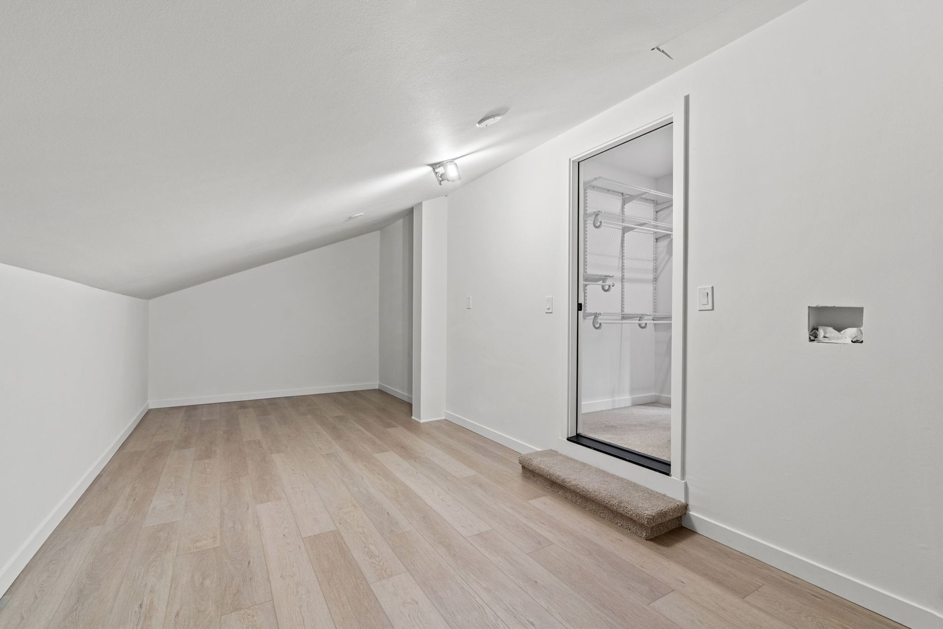 An empty room with hardwood floors and white walls.