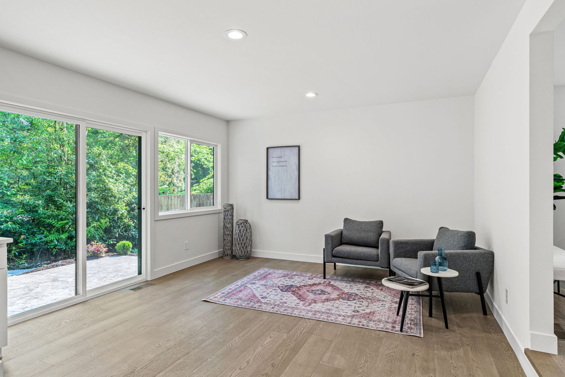 A living room with two chairs , a rug and a sliding glass door.