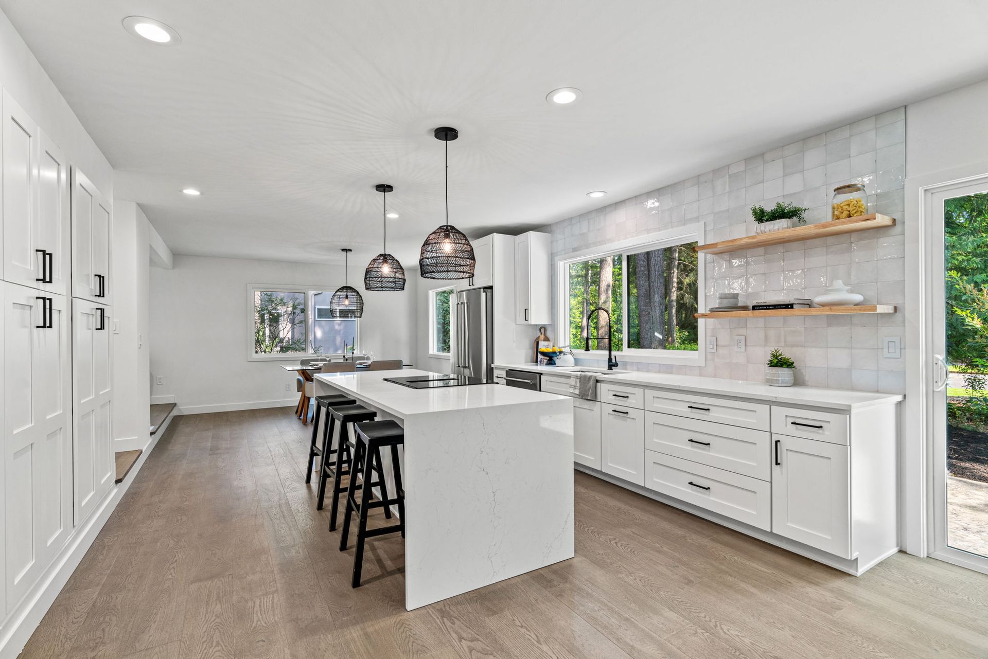 A kitchen with white cabinets and stools and a large island in the middle.