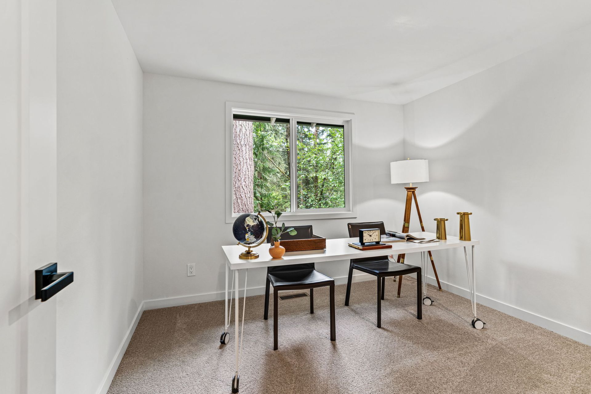 A room with a desk and chairs in it and a window.